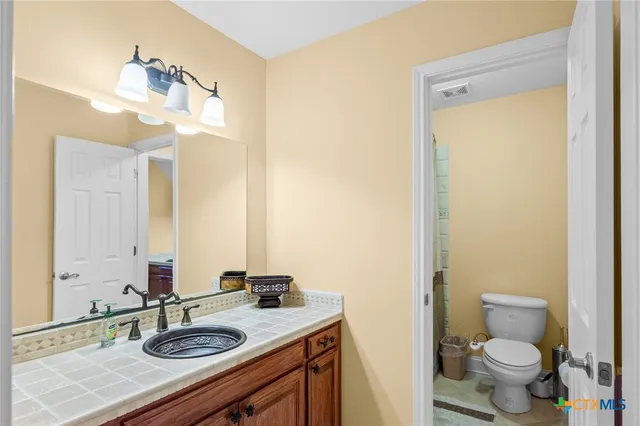 a bathroom with a sink vanity granite toilet and a mirror