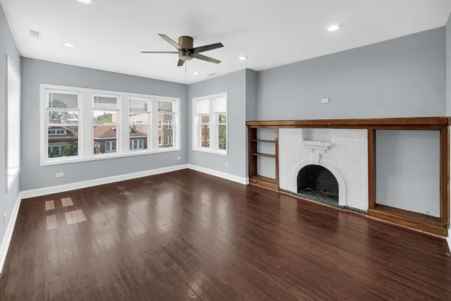 a view of empty room with wooden floor and fireplace