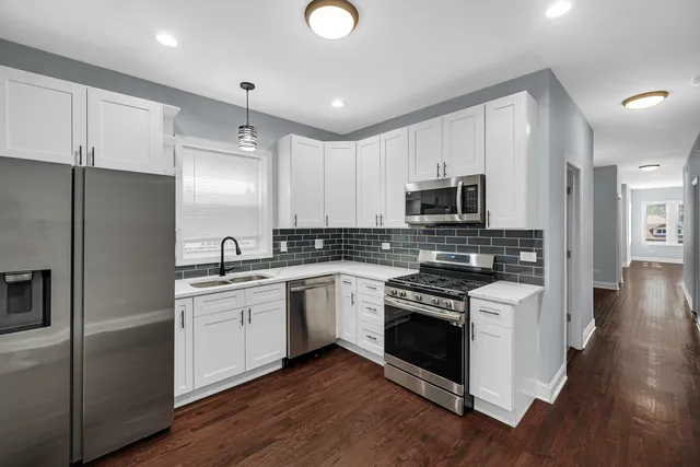 a kitchen with a sink cabinets stainless steel appliances and wooden floor