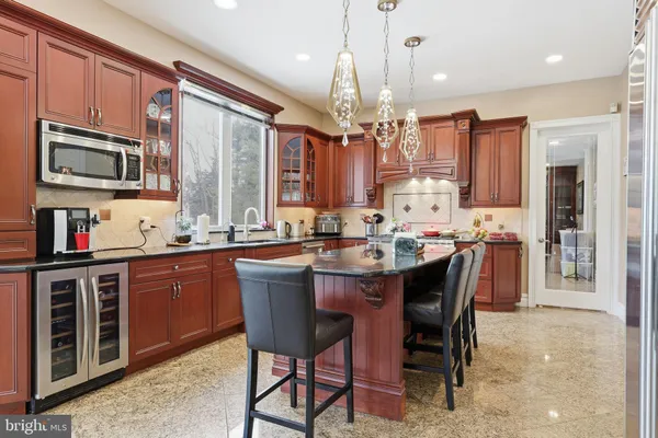 a open kitchen with stainless steel appliances granite countertop a stove top oven a sink dishwasher a dining table and chairs with wooden floor