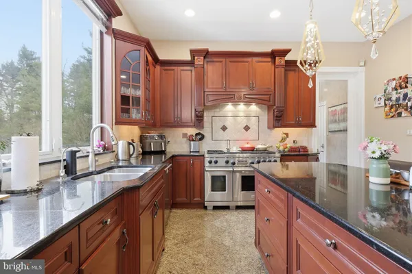 a kitchen with stainless steel appliances granite countertop a stove a sink dishwasher a dining table and chairs with wooden floor