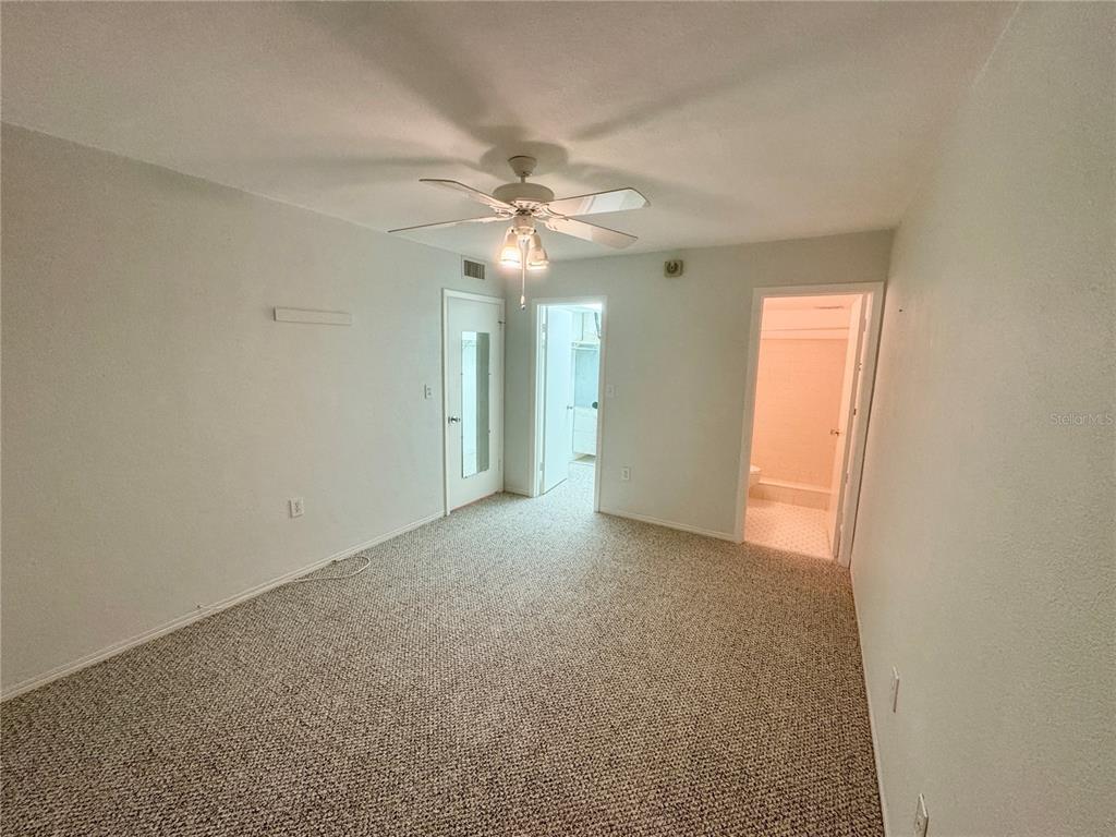 11201 80th Avenue, Unit 101 Seminole, FL 33772 - Photo 15 of 31 an empty room with chandelier fan and windows