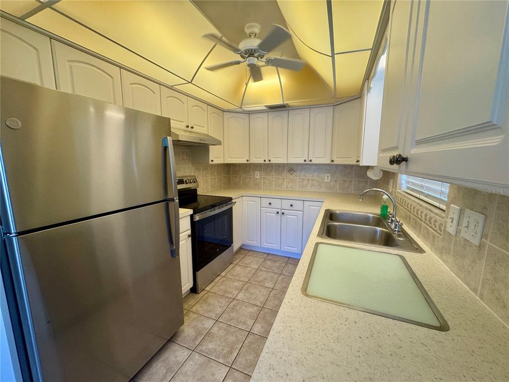 11201 80th Avenue, Unit 101 Seminole, FL 33772 - Photo 5 of 31 a kitchen with stainless steel appliances granite countertop a refrigerator a sink dishwasher and white cabinets