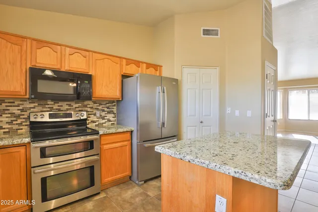 a kitchen with stainless steel appliances granite countertop a stove refrigerator and microwave