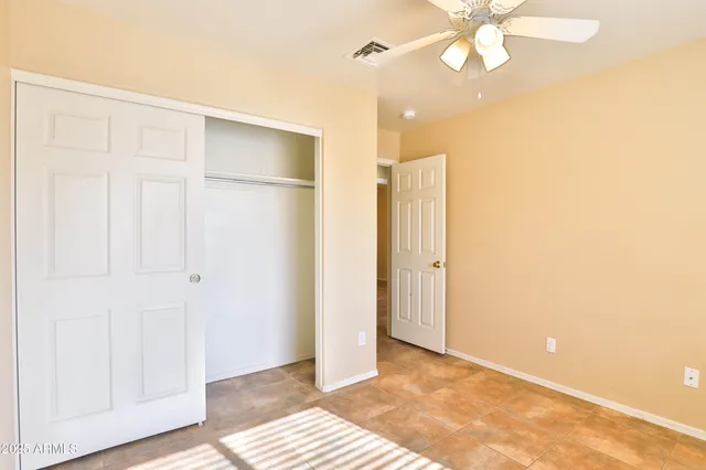 a view of an empty room with wooden floor and a ceiling fan