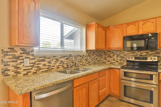 a kitchen with granite countertop a sink stainless steel appliances and cabinets