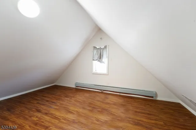 a view of an empty room with wooden floor and windows