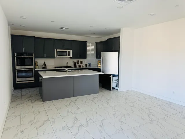 a kitchen with stainless steel appliances a sink a stove a microwave a refrigerator a cabinets and a window