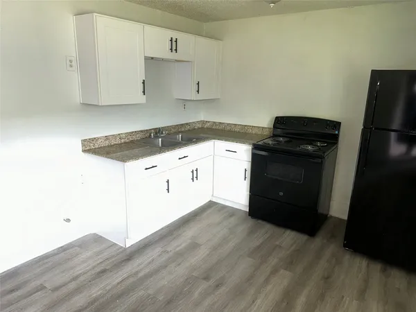 a kitchen with granite countertop white cabinets and black appliances