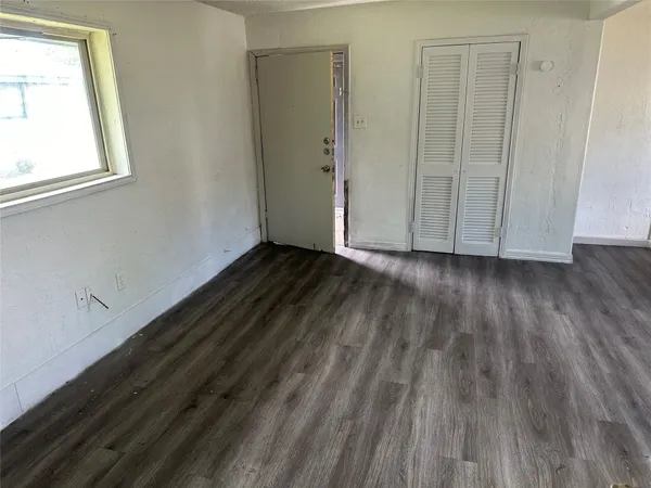 a view of an empty room with wooden floor and a window