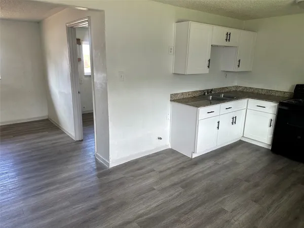 a kitchen with granite countertop white cabinets and black appliances