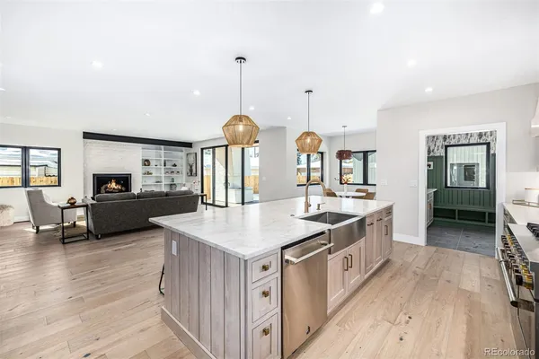 a large kitchen with stainless steel appliances a large counter top a sink a stove and a wooden floors