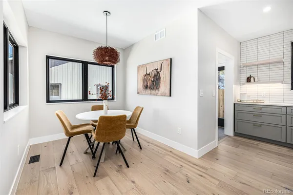 a dining room with wooden floor a chandelier a wooden table and chairs