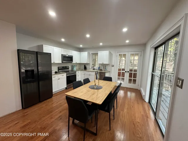 a kitchen with stainless steel appliances granite countertop a refrigerator a sink a stove a dining table and chairs