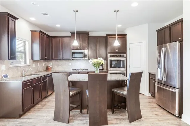 a kitchen with stainless steel appliances granite countertop a refrigerator a stove a sink and a refrigerator