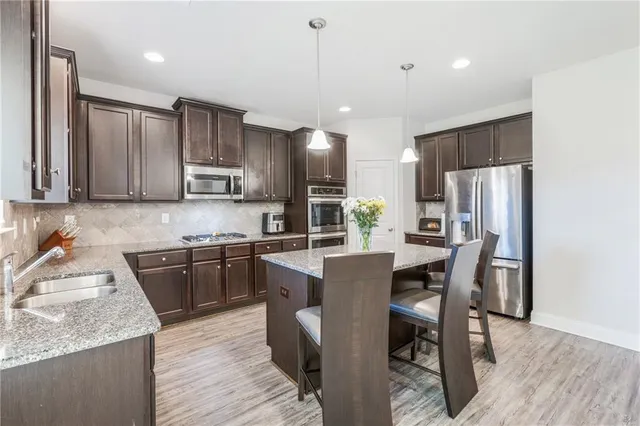 a kitchen with stainless steel appliances granite countertop a table chairs sink refrigerator and microwave