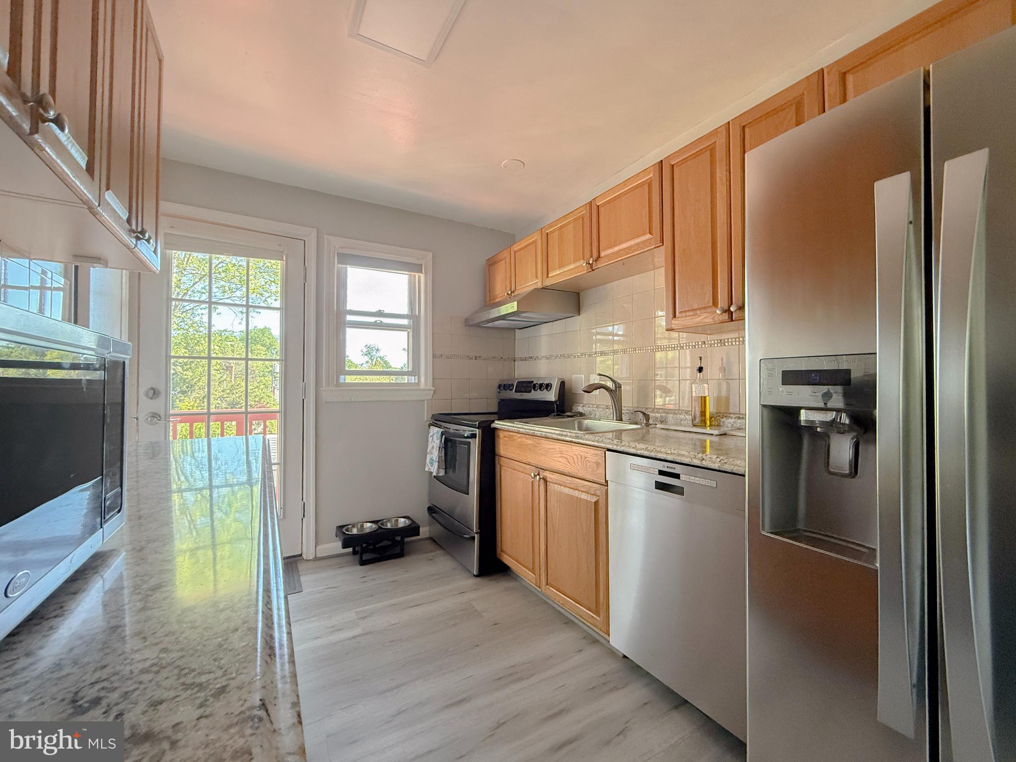 11601 Veirs Mill Road Wheaton, MD 20902 - Photo 13 of 30 a kitchen with granite countertop a refrigerator a sink a stove and cabinets