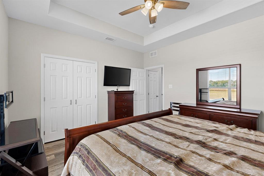 634 Gant Road Sherman, TX 75090 - Photo 26 of 40 Bedroom featuring a tray ceiling, a ceiling fan, wood finished floors, and a closet