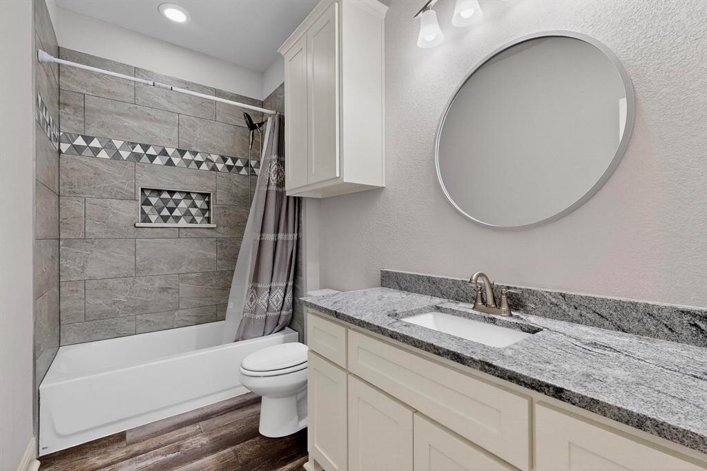 634 Gant Road Sherman, TX 75090 - Photo 27 of 40 Full bathroom featuring shower / tub combo with curtain, dark wood-style floors, vanity, and a textured wall