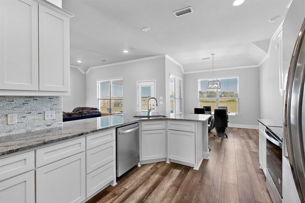 634 Gant Road Sherman, TX 75090 - Photo 5 of 40 Kitchen featuring tasteful backsplash, light stone counters, stainless steel appliances, white cabinetry, and crown molding