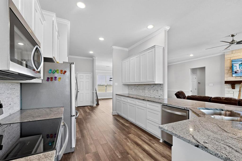 634 Gant Road Sherman, TX 75090 - Photo 8 of 40 Kitchen with stainless steel appliances, white cabinetry, a ceiling fan, light stone countertops, and dark wood-style flooring