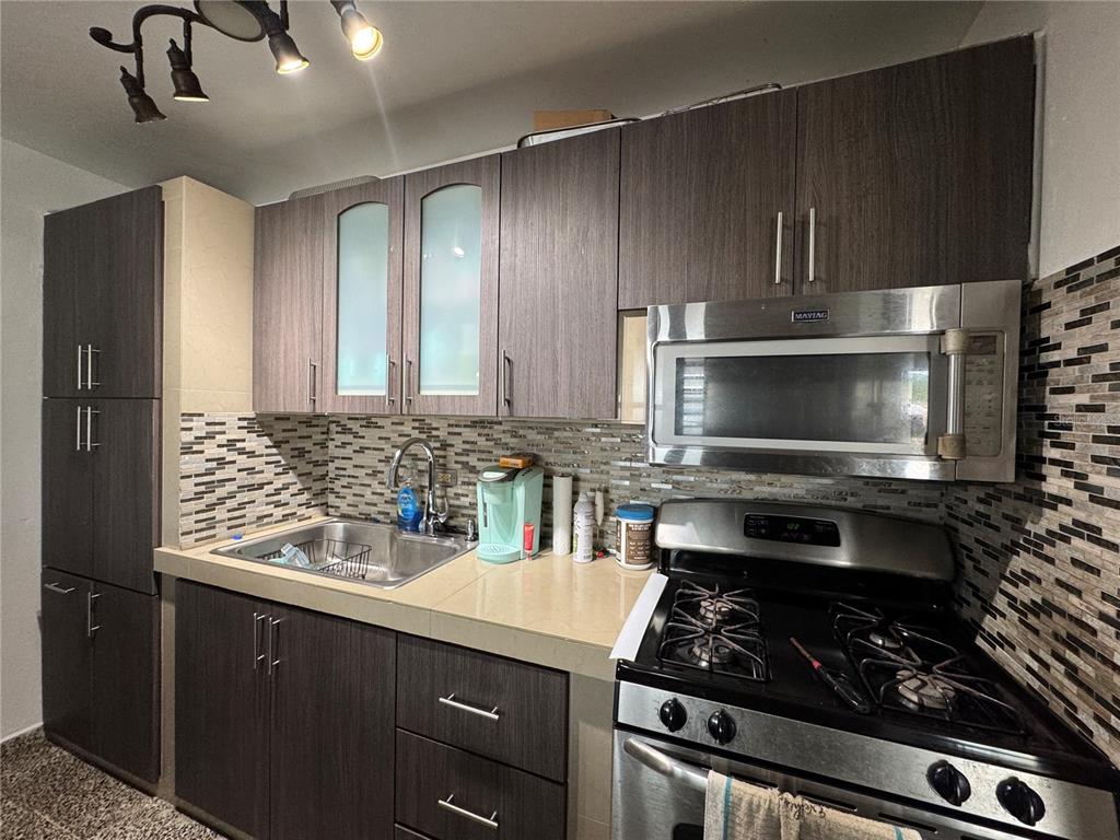 140 Km 38.9 Utuado, Utuado 00641 - Photo 28 of 55 a kitchen with a stove a microwave and wooden cabinets