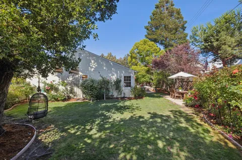 a backyard of a house with table and chairs under an umbrella