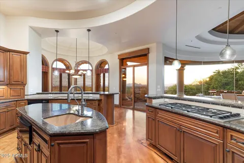 a kitchen with stainless steel appliances granite countertop a sink a stove and a wooden cabinets