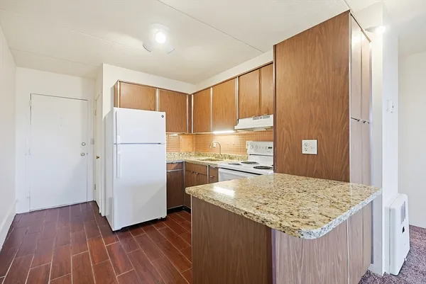 a kitchen with kitchen island a counter top space a sink a refrigerator and wooden floor