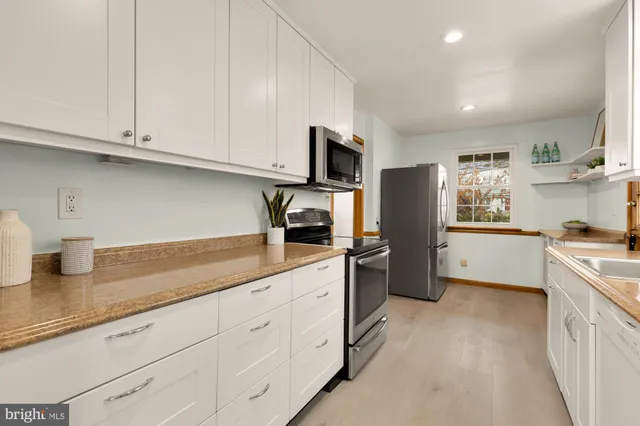 a kitchen with granite countertop white cabinets and stainless steel appliances