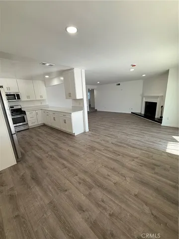 a view of a kitchen with kitchen island a sink wooden floor and electronic appliances