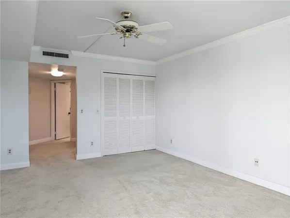 an empty room with chandelier fan and windows