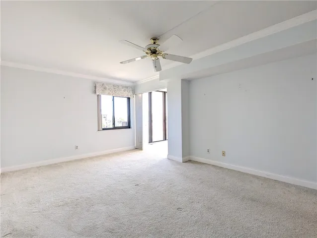 an empty room with chandelier fan and windows