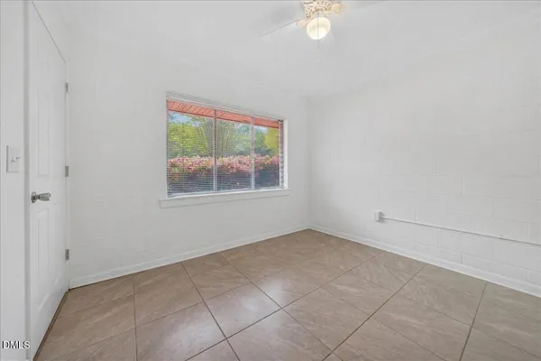 an empty room with windows and fan