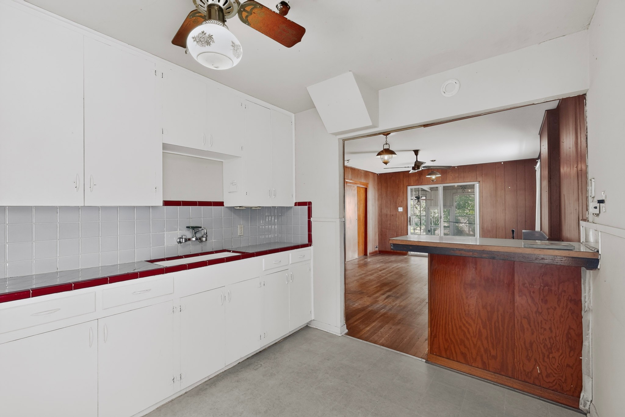 4703 Leslie Avenue Austin, TX 78721 - Photo 24 of 34 A well-lit kitchen with white cabinetry and a convenient pass-through window overlooking an adjoining room.