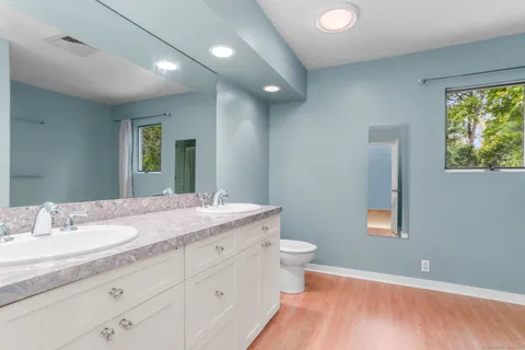 a bathroom with a granite countertop sink a toilet and a mirror