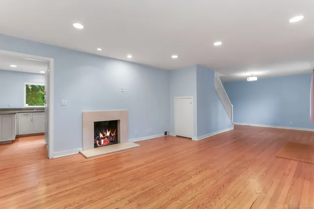 a view of an empty room with wooden floor a fireplace and a window
