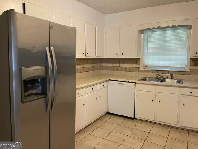 a kitchen with white cabinets and refrigerator