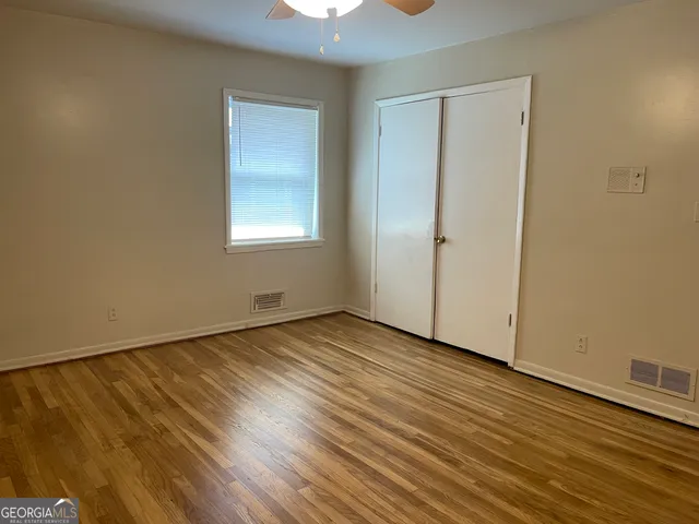 a view of an empty room with wooden floor and a window