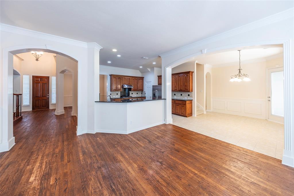 220 Justin Road Murphy, TX 75094 - Photo 12 of 40 Unfurnished living room with arched walkways, crown molding, wood finished floors, a chandelier, and recessed lighting