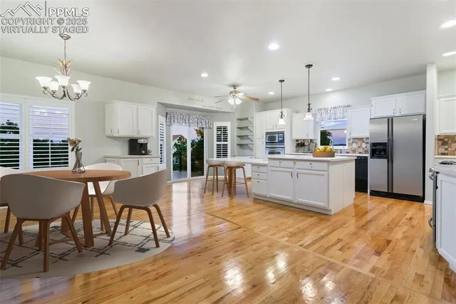 a view of an empty room with wooden floor and a chandelier fan