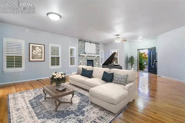 a living room with couches and kitchen view with wooden floor