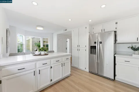 a kitchen with white cabinets and refrigerator