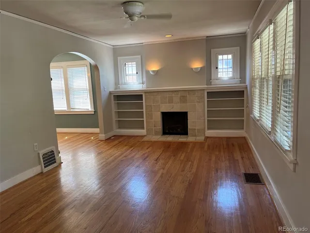an empty room with wooden floor fireplace and windows