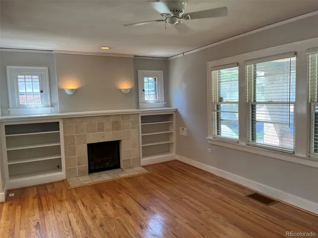 a view of an empty room with wooden floor fireplace and a window