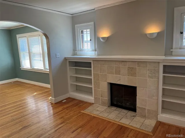 an empty room with wooden floor fireplace and windows