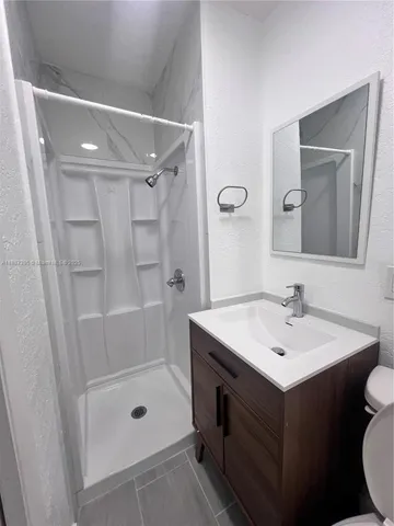 a bathroom with a sink a toilet a mirror and shower