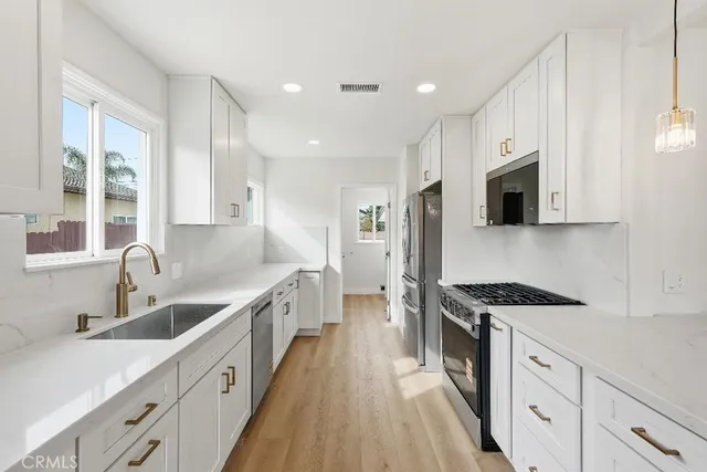 a kitchen with kitchen island granite countertop a sink a counter space stainless steel appliances and cabinets