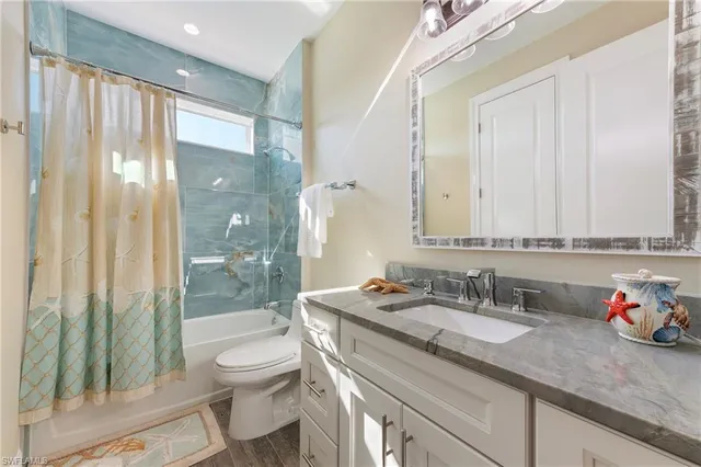 a bathroom with a granite countertop sink toilet a mirror and shower