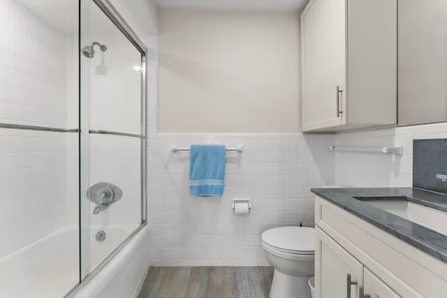 a bathroom with a granite countertop toilet a sink and shower